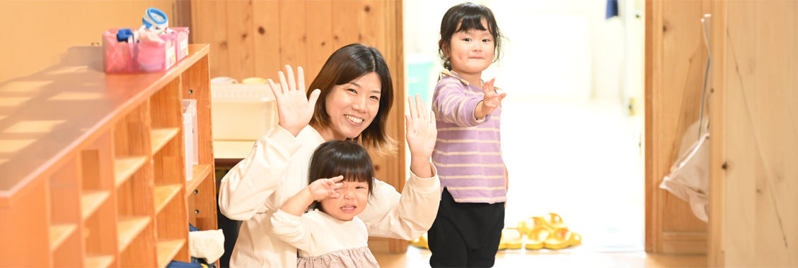 園児と保育士が手を振っている