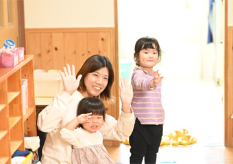 手を振っている園児と保育士
