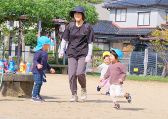 園庭で遊ぶ園児と保育士